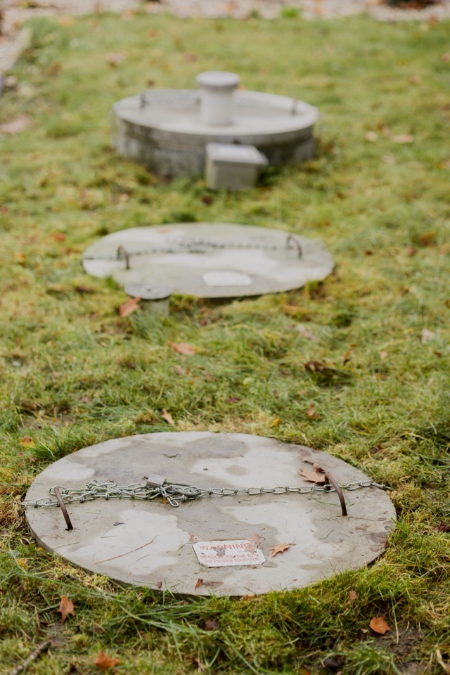 Three septic tank covers visible at ground level in a lawn