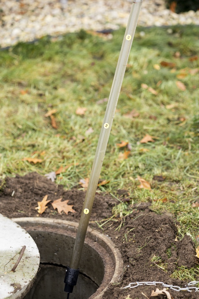 Measurement rod with numbered level markers inside an open tank